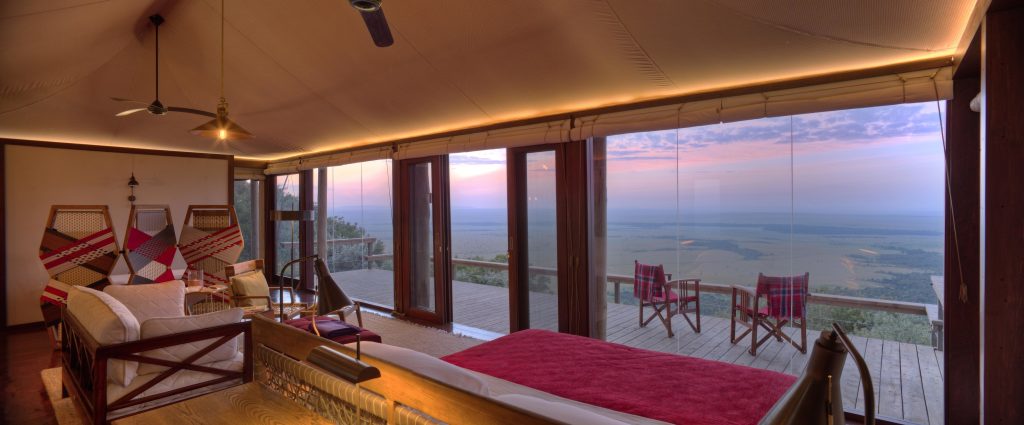 Luxury safari lodge bedroom with panoramic views over Mara plains at sunrise in Kenya