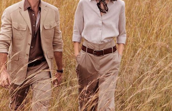 Couple in safari clothing walking through golden grassland on African adventure travel experience